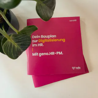 Gedruckte geno.HR-PM Broschüren auf einem Tisch neben einer Zimmerpflanze